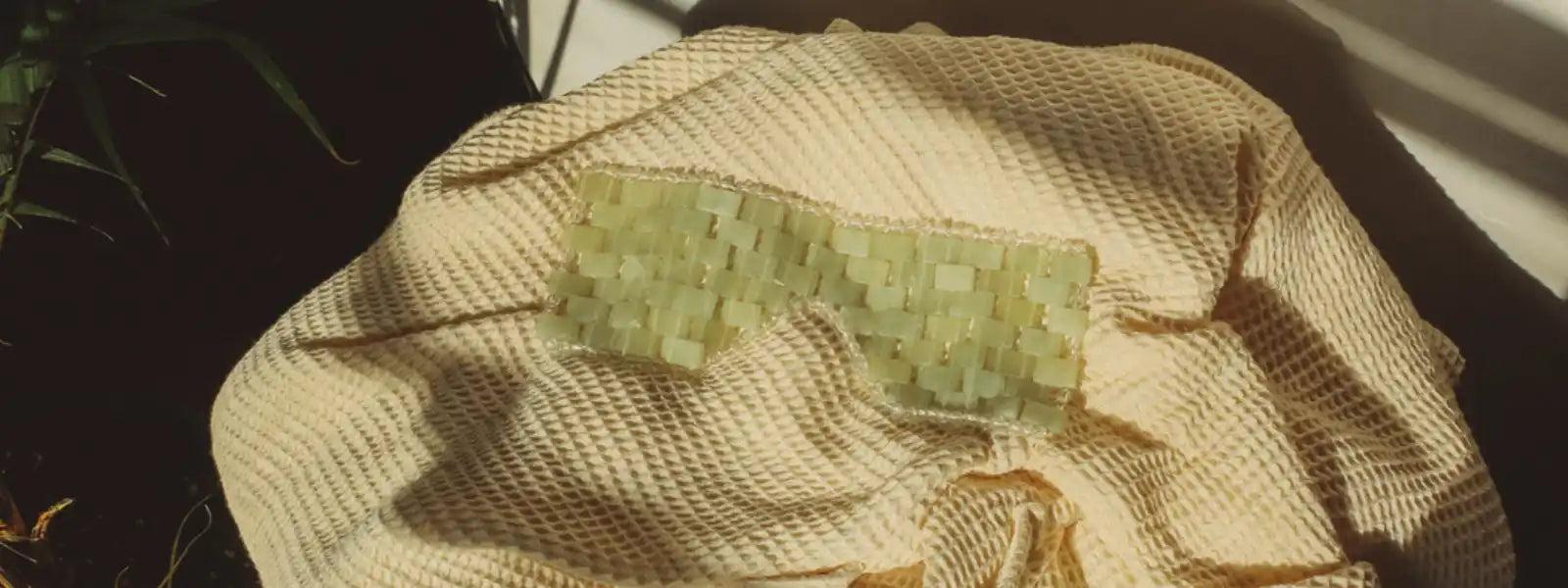 Jade-colored sunglasses resting on a beige textured fabric.