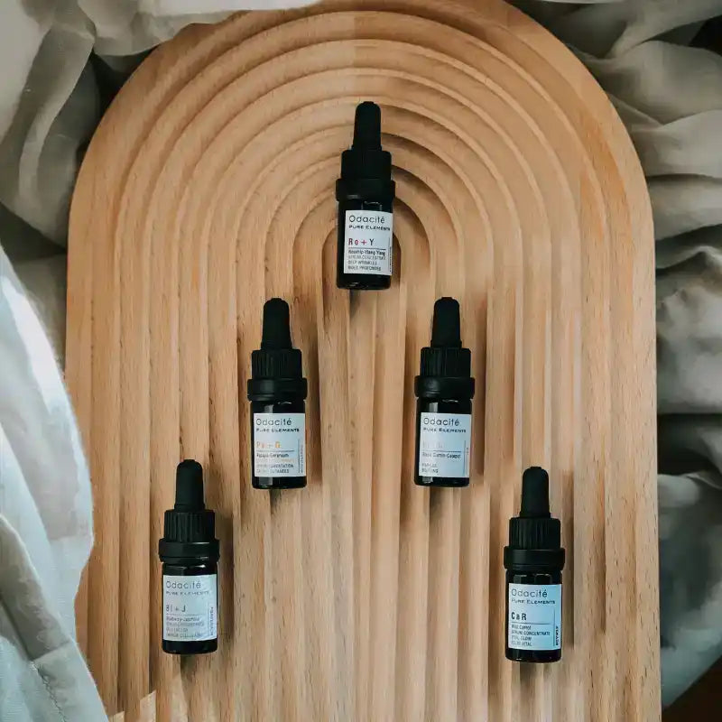 Wooden arch-shaped display board with five dropper bottles arranged symmetrically.